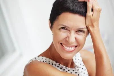 woman smiling after getting ceramic dental implants to help restore her smile