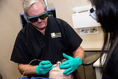 Dr. Lynn of Lynn Dental Care in Dallas, TX performing a laser dentistry procedure on a patient